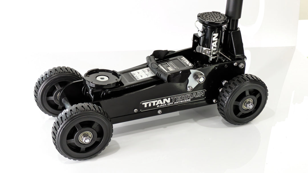 A black rugged floor jack with a hydraulic pump and four large wheels, designed for off-road conditions.