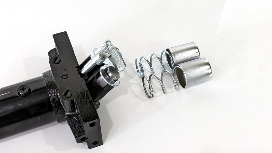 Replacement pump unit for a black rugged floor jack, consisting of metal springs, bolts, and other components.